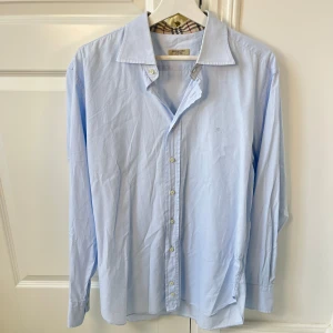 Burberry skjorta - Inga som helst defekter, storlek 42 vilket motsvarar ungefär L. Stor på mig som är 180,75 kg. Kom med frågor! Kanske ser ut som en missfärgning eller likande men det är bara galgen som syns igenom! 