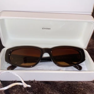Bruna solglasögon från CHIMI - Snygga bruna solglasögon från CHIMI och mörktonade linser. Glasögonen har en stilren design och kommer i originalfodral och påse. Perfekta för dig som vill ha en clean look även helt oanvända.