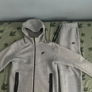 Grå Nike Tech - Snygga ljusgrå nike tech. Perfekta för chill eller träning, med en clean och sportig look. Storlek M och är i mycket bra stick. Upphämtning finns i Svedmyra!! Om ni undrar något så är det bara skriva!
