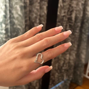 Silvrig ring med hjärtformad design - Säljer denna ring då den tyvärr inte kommer tills användning längre, ringen är justerbar! 🤍
