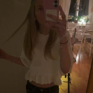 Vit croppad blus med volang - Supersöt vit blus med croppad passform och volangdetaljer både vid ärmslut och nederkant. Bättre bild se bild 3&4💕 använd 1 gång