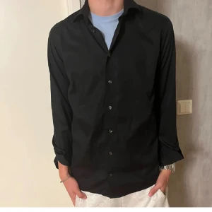 Svart skjorta från Eton - Svart eton skjorta i storlek 38 (passar ungefär M). Modellen är 185 och väger 70. Skjortan är i väldigt bra skick 9/10 inte så använd. Skriv vid frågor eller liknande!