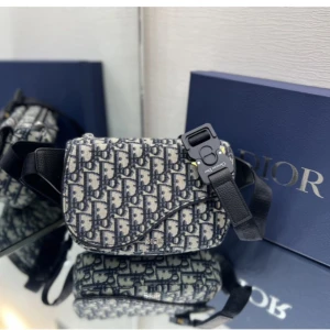 Dior axelväska i blått monogram - Snygg axelväska från Dior med klassiskt blått och vitt monogrammönster. Väskan har justerbar svart rem med robust spänne i metall och läderdetaljer. Perfekt storlek för det viktigaste och en riktigt trendig accessoar.