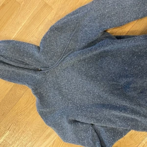 Grå fleecejacka med huva - Mysig grå fleecejacka med huva, perfekt för kyliga dagar. Jackan har en dragkedja framtill och långa ärmar. Idealisk för både vardag och utomhusaktiviteter.