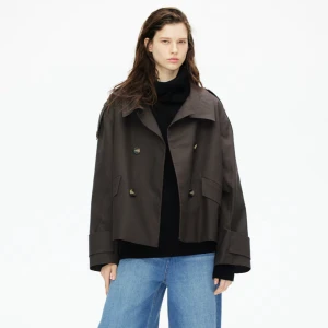 Brun trenchcoat med knappar - Snygg brun trenchcoat med dubbelknäppning och bred krage. Jackan har en oversized passform och långa ärmar med knappar vid ärmsluten. Perfekt för höst och vår.