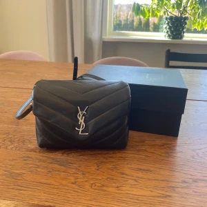 Ysl väska - Säljer nu min ysl loulou toy bag i svart med silvriga detaljer. Jag köpte den 2022 och den har inte användes så mycket sen dess. Väskan är i väldigt bra skick. Har några få slitningar på skinnet, tex under väskan på kanterna. Se bilder. Inget som är märkbart och väskan ser i helhet väldigt bra ut. Kvitto finns samt dustbag, box och andra lappar som skickades med vid köp. Avtagbar och justerbart axelband. Väskan kostar nu upp mot 16000kr att köpa ny💕  