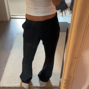 Svarta kostymbyxor - Snygga svarta kostymbyxor med låg midja och en rak passform. Perfekta för en stilren look. Byxorna har en klassisk design med diskreta fickor.