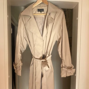 Beige trenchcoat från KappAhl - Beige trenchcoat från KappAhl med klassisk design. Perfekt för vår och höst. Lite oversized, känns mjuk och bekväm att ha på sig. Knappt använd ☺️