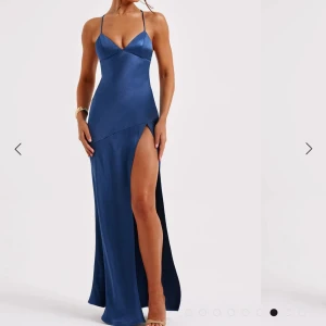 Blå långklänning med slits - Elegant blå långklänning med smala axelband och slits. Klänningen har en öppen rygg med snörning. Den är i ett fint sidenmaterial med innertyg. Aldrig använd med lapparna kvar🤍