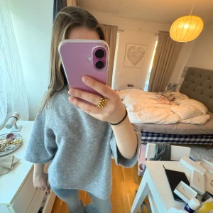 Grå tröja från & Other Stories - Säljer en stilren grå tröja från & Other Stories. Tröjan har en mjuk och fluffig textur med en avslappnad passform. Perfekt för kyligare dagar och enkel att matcha med olika outfits. Tröjan är nästan aldrig använd.