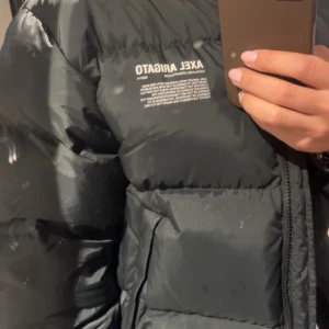 Svart pufferjacka från Axel Arigato - Säljer en stilren svart pufferjacka från Axel Arigato. Jackan är i storlek s.