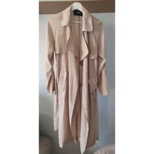 Beige trenchcoat från Bik Bok - Snygg beige trenchcoat från Bik Bok med klassisk design. Jackan har långa ärmar och ett bälte i midjan för en stilren look. Inköpt för ca 700kr 💛 Perfekt till vår o sommar