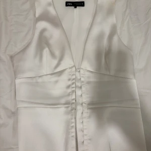 Vit sidenväst från Zara - Elegant vit väst från Zara i sidenmaterial. Västen har en stilren design med knappar framtill och en v-ringad hals. Perfekt för en chic och sofistikerad look.Skriv innan köp💓