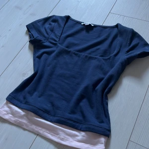 Mörkblå topp från Subdued - Säljer en mörkblå topp från Subdued med korta ärmar och en ljusrosa kant nedtill. Aldrig använd, och den är i super duper bra skick! 💞Den är i S men sitter som en XS. Den är lite kroppad också, på mig så går den precis nedanför naveln. Om du undrar över något så skriv till mig! 🤗