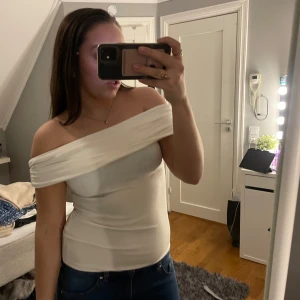 Vit offshoulder topp från Amisu - Säljer en stilren vit offshoulder topp från Amisu. Toppen har en elegant design med en bred krage som vilar över axlarna. Perfekt för en chic och modern look. Passar bra till både jeans och kjol. 🌟Använd endast en gång! Är u strl L men passar S❤️