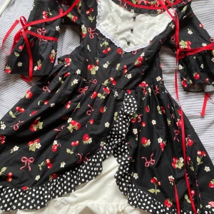 lolita klänning 🍓 - En jättesöt klänning med vit underkjol, trekvartsärm och jordgubbsmönster. Vad mer kan man vilja ha?? Perfekt för tebjudningar, animefestivaler och picknickar. Den går att justera något. Passar S-M