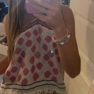 halterneck topp från Zara - En söt vit och rosa topp från Zara med prickigt mönster och dekorativa pärlor vid halsen. Toppen är ärmlös och har en halterneck-design. Perfekt för varma sommardagar! Använt ungefär 2 gånger och köpt för några månader sen. prisförslag kan gärna ges!