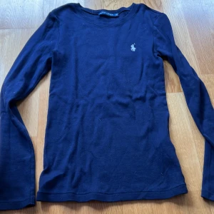 Mörkblå långärmad tröja från Ralph Lauren XS - Säljer en stilren mörkblå långärmad tröja från Ralph Lauren med det klassiska logotypbroderiet på bröstet. Perfekt för en avslappnad men ändå elegant look. Passar bra till jeans eller kjol.