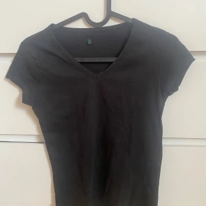 Svart t-shirt från Benetton - Snygg svart t-shirt från Benetton med v-ringning och korta ärmar.Diskret logga på bröstet. Liten i storleken 