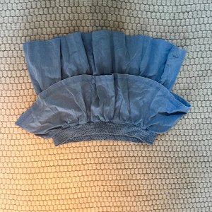 Blå volangkjol - Säljer en söt blå kjol med volanger och elastisk midja. Perfekt för en avslappnad och stilren look. Kjolen är kort och har en luftig passform.