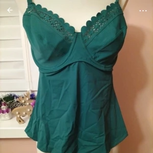 Grön tankini från Bonprix - Säljer en snygg grön tankini från Bonprix med justerbara axelband och dekorativ spetsdetalj upptill. Den har en smickrande passform och är perfekt för en stilren look. Storlek 44 ( 85 D)