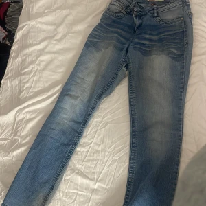 Blå jeans från l.e.i. - Snygga blå jeans från l.e.i. med låg midja och bootcut-stil. De har en klassisk femficksdesign och dekorativa sömmar på bakfickorna. Perfekta för en avslappnad look. Håll vid låten därför de låga priset 