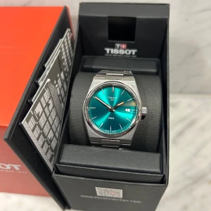 Tissot PRX 35mm - Säljer en Tissot PRX klocka med grön urtavla i mycket bra skick. 100% original   PRX 35mm Unisex Watch T137.210.11.081.00 Green Dial Steel Bracelet   Dial Colour Green Glass Type Sapphire Crystal Case Width (mm) 35.00 Watch Case Material Stainless Steel Watch Case Colour Silver