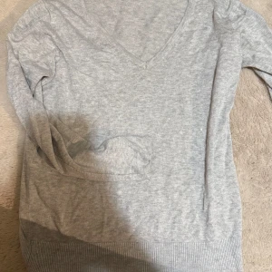 Grå v-ringad tröja från 157 - Säljer en stilren grå v-ringad tröja från 157. Tröjan har långa ärmar och är perfekt för en avslappnad look. Den är tillverkad i ett mjukt material som gör den bekväm att bära hela dagen.