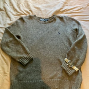 Ralph louren tröja - Säljer en stilren grå stickad tröja från Polo Ralph Lauren. Tröjan har en diskret logga på bröstet och ribbade muddar vid ärmslut och nederkant. Perfekt för kyligare dagar! Nyskick! Inga defekter 