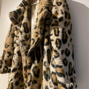 Leopardmönstrad pälsjacka - Snygg och trendig leopardmönstrad pälsjacka med långa ärmar. Perfekt för att göra ett statement i vinter. Jackan har en klassisk krage och är gjord i ett mjukt material som ger en lyxig känsla.