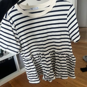 Randig blus från Zara - Säljer en söt randig blus från Zara med korta ärmar och volangdetalj i nederkant. 