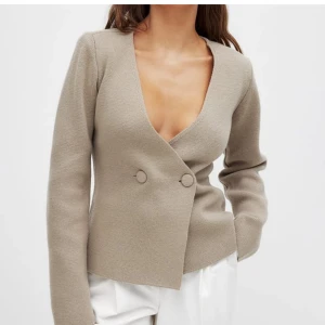Beige omlottkofta med knappar - Snygg beige omlottkofta med v-ringning och dekorativa knappar framtill. Perfekt för en stilren look. Passar bra till både jeans och kjol. Ifrån Moa Matsson kollektion tillsammans med NAKD helt slutsåld. Säljer endast vid bra bud