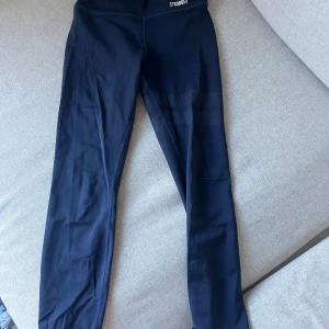 Mörkblå leggings från Stronger - Snygga mörkblåa leggings från Stronger. Perfekta för träning med en tight passform och hög midja. Tillverkade i ett stretchigt syntetmaterial som ger bra rörelsefrihet. Diskret mönsterdetalj på låren. Pris kan diskuteras och jag är villig till att sänka priset!!!