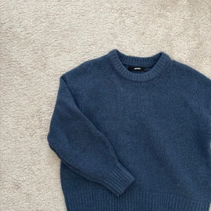 Blå stickad tröja från BikBok - Säljer en mysig blå stickad tröja från BikBok. Tröjan har en rund halsringning och långa ärmar med ribbade muddar. Perfekt för kyliga dagar!