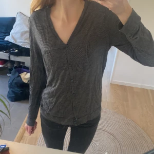 Grå kofta med knappar - Säljer en stilren grå randig kofta med knappar framtill. Den har en v-ringad design. Sälj då den inte kommer till användning! Liten i storleken. Pris kan diskuteras 💕