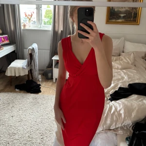 Röd klänning från FAVOLOOK - Snygg röd klänning från FAVOLOOK med v-ringad design och omlott-detalj. Perfekt för en kväll ute eller en speciell tillställning. Klänningen har en figurnära passform som framhäver silhuetten. Storleken är S men skulle säga att den passar M oxå💕Klänningen har inga defekter men har används flitigt, öppen för prisförslag!🥰