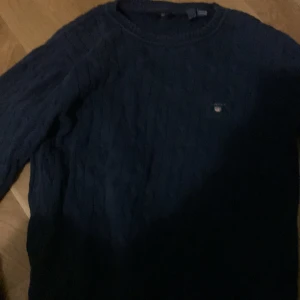 Mörkblå stickad tröja från GANT - Säljer en stilren mörkblå stickad tröja från GANT. Tröjan har ett diskret märke på bröstet och är perfekt för kyligare dagar. Passar ungdomar i åldern 13-17 år.skick bra 
