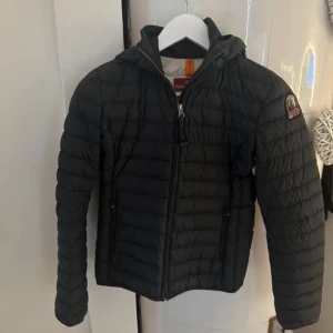 Svart dunjacka från Parajumpers - Säljer en svart dunjacka från Parajumpers med huva och dragkedja. Jackan har ett märke på ärmen. Den är stilren och funktionell med en quiltad design. Använd med i sparsamt skick, finns en defekt på vänster innerficka. Köpt på kidsbrandstore och storlek är young medium! skriv vid frågor om storleken!!