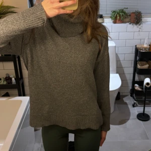 Grå stickad polotröja/turtleneck - Mysig grå stickad polotröja. Tröjan har en hög polokrage och långa ärmar, perfekt för kyliga dagar. Den har en avslappnad passform med ribbade muddar vid ärmslut och nederkant.