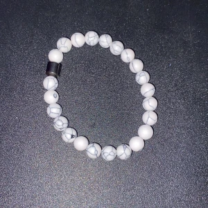 Vitt pärlarmband med marmormönster - Snyggt vitt armband med marmormönstrade pärlor. Armbandet har en enkel och stilren design som passar perfekt till alla tillfällen. Det elastiska bandet gör det lätt att ta på och av.