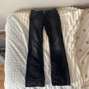 Svarta bootcut jeans Gina Tricot - Snygga svarta jeans från Gina Tricot i bootcut-modell. Jeansen har klassisk femficksdesign, svarta sömmar och lätt slitna detaljer framtill. Perfekta för dig som gillar en tidlös look med lite extra edge.