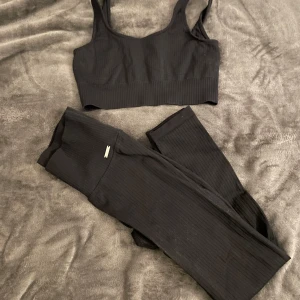 Svart ribbad linnetopp från Aim'n - Svart ribbad linnetopp från Aim'n, perfekt för träning. Topp med breda axelband och croppad passform. Tillverkad i stretchigt material som sitter skönt och följer kroppen. Enkel och stilren design som funkar till alla träningspass.