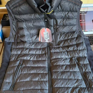 Svart dunväst från Parajumpers - Finns i alla storlekar! Snygg svart dunväst från Parajumpers med quiltad design och dragkedja framtill. Västen har två praktiska fickor med dragkedja och en hög krage. Perfekt för lager-på-lager och stilren look under kyliga dagar.