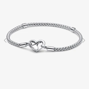 Pandora armband med berlocker - Snyggt silverfärgat Pandora armband med flera berlocker, bland annat ett hjärta och en söt figur med ett litet guldhjärta. Armbandet har detaljer med glittrande stenar och klassisk flätad kedja. Perfekt accessoar för att lyfta din stil. 