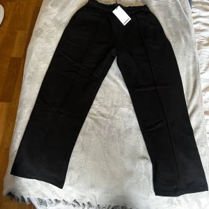 Svarta mjukisbyxor från Bershka M - Svarta mjukisbyxor från Bershka i storlek M med elastisk midja och raka ben. Byxorna har en clean look och är tillverkade i mjukt material som känns skönt mot huden. Perfekta för en chill och avslappnad stil.