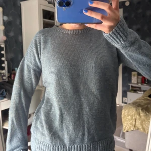 Blå stickad tröja med rund hals - Mysig blå stickad tröja med rund halsringning och ribbade muddar vid ärmslut och nederkant. Perfekt för lager-på-lager och chill dagar. Enkel och stilren design som funkar till jeans eller kjol.