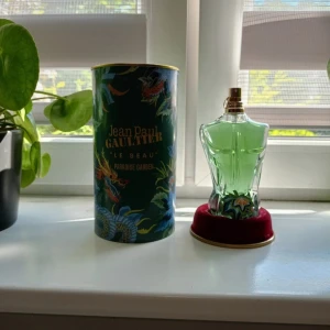 Jean Paul Gaultier Le Beau Paradise Garden - Jean Paul Gaultier Le Beau Paradise Garden EdP 125ml. Flaskan är formad som en manlig torso i glas med grön parfymvätska och detaljerad botten. Kommer i en dekorativ, mörkgrön burk med tropiskt mönster och guldtext. Lyxig och unik design – perfekt för dig som gillar statement-parfymer.