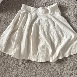 Vit kortkjol i bomull - Snygg vit kortkjol med utsvängd form och bred midja. 