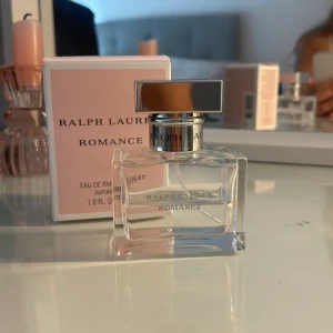 Ralph Lauren Romance EdP 30ml - Ralph Lauren Romance Eau de Parfum 30 ml med en elegant, fyrkantig glasflaska och silverfärgat lock. Doften kommer i en ljusrosa kartong med stilren design. Perfekt för dig som gillar fräscha och romantiska parfymer med en feminin touch.