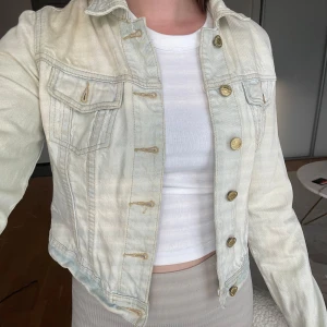 Jeansjacka från Gina Tricot  - Ljusblå jeansjacka från Gina Tricot med guldfärgade knappar. Mycket gott begagnat skick
